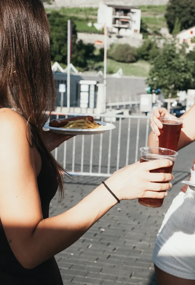 Gast mit einem Glas und einem Teller Pommes vor den Bergen
