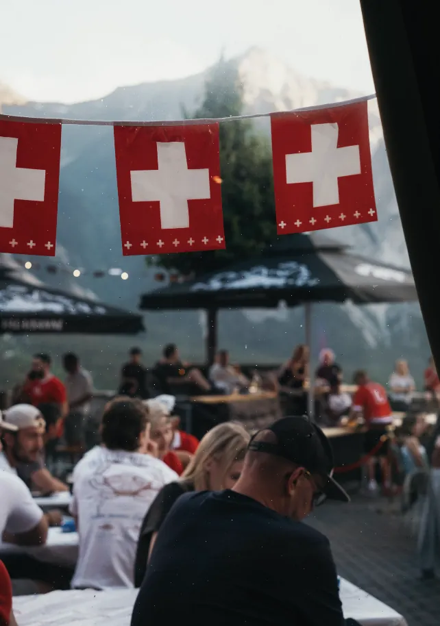 Schweizer Fähnchen über dem Publikum auf dem Rathausplatz, im Hintergrund die Walliser Berge